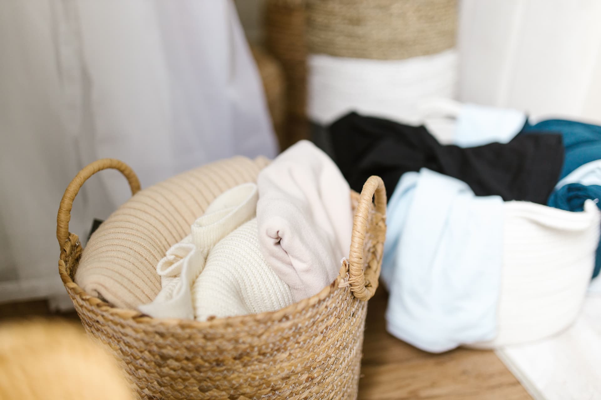 Soft clothes organized inside woven laundry baskets in a quiet, tidy indoor corner.